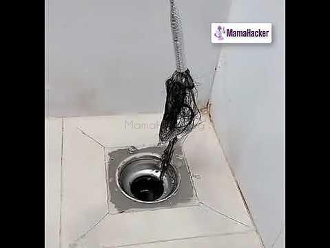 Метална кука DrainCleaner в действие, отпушваща канал с косми и замърсявания. Идеален инструмент за лесно чистене на канали.